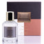 A clear glass bottle of 'Tantrico' eau de parfum with a gold-colored cap, placed next to its purple and pink box packaging that has the brand name and product title visible.